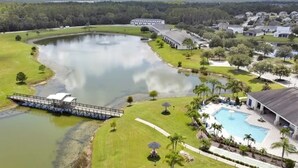 A golf course with a large pond, a bridge, and a swimming pool surrounded by residential buildings. - 2632 Remodeled Getaway -heart of Disney (Kissimmee)