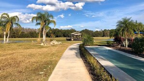 A pathway leading to a gazebo in a park with palm trees and a small pond. - 2632 Remodeled Getaway -heart of Disney (Kissimmee)