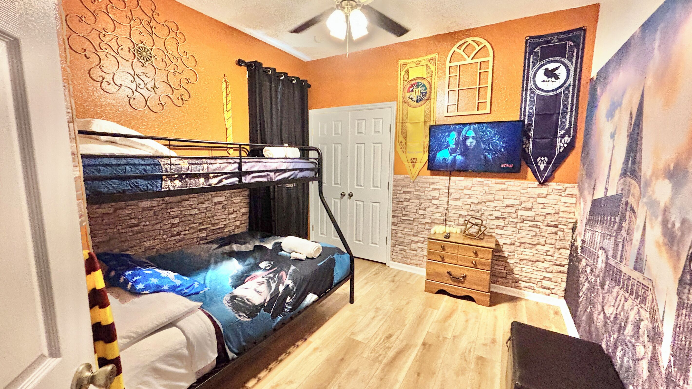 A room with bunk beds, a dresser, a door, and a wall with a mural.