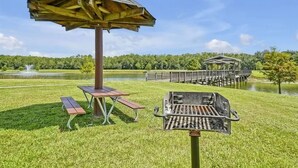 A picnic area with a grill, a wooden pavilion, and a dock over water. - 2632 Remodeled Getaway -heart of Disney (Kissimmee)