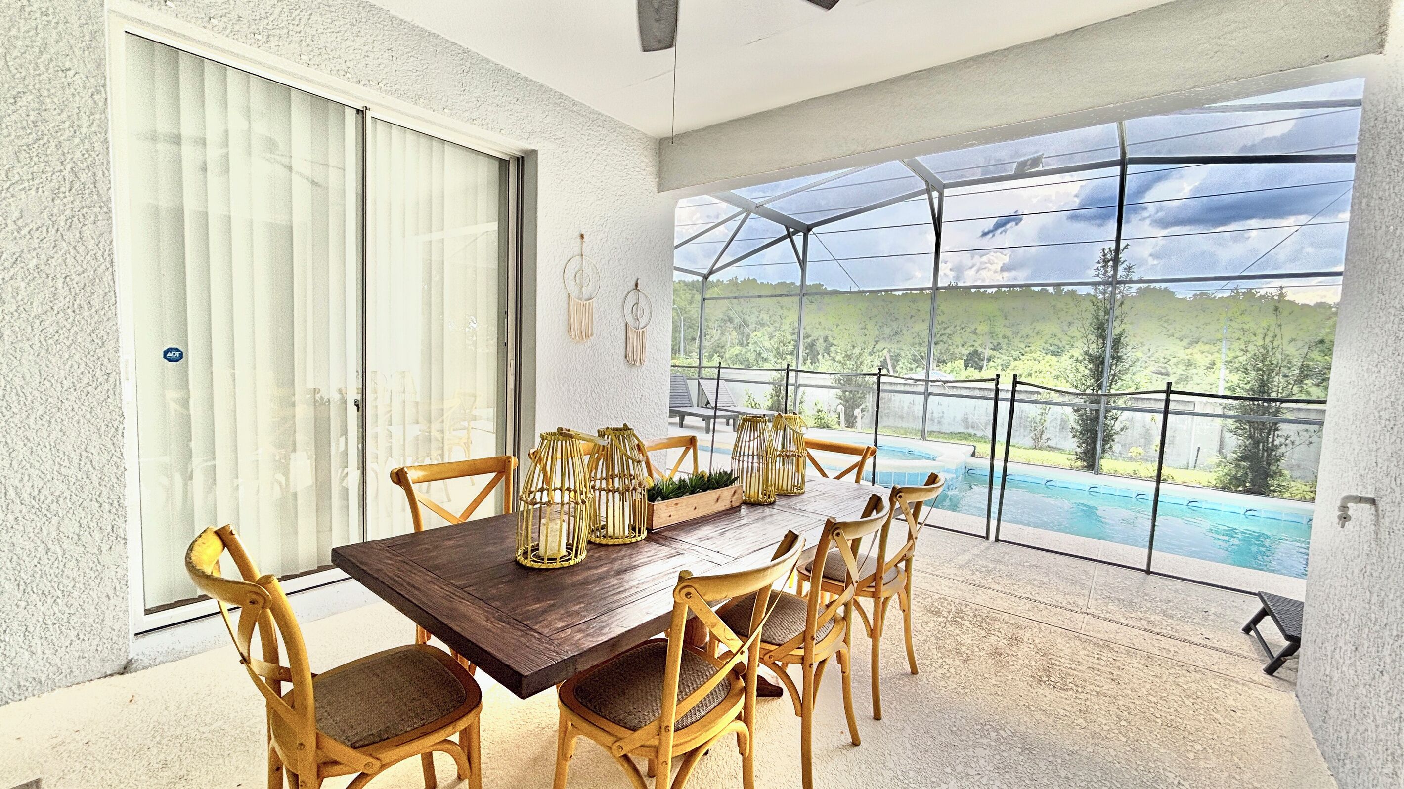 A dining area with a table and chairs, a view of a swimming pool, and a glass door leading outside.