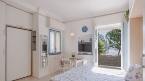 A bedroom with a bed, a desk, and a view of the outdoors. - Laccadiva by Interhome (Zoagli)
