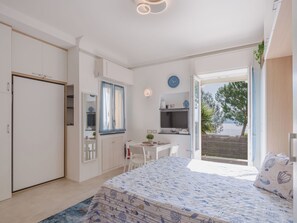 A bedroom with a bed, a desk, and a view of the outdoors. - Laccadiva by Interhome (Zoagli)