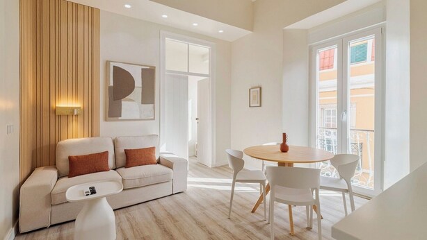 Una sala de estar moderna con sofá, mesa de centro y zona de comedor.