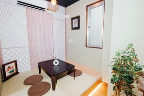 A room with tatami mats, a dark wooden table, a small plant, and a framed picture on the wall. - NEWOPEN Campaign now convenient transportation 1 stop from Namba, 5 min walk from Daikokucho station 4 rooms +2 toilets 2 shower rooms spacious accommodations (Naniwa Ward, Osaka)