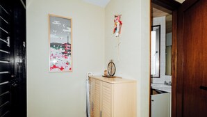 Ein Flur mit einem Holzkleiderkasten, einem gerahmten Bild eines traditionellen Gebäudes und einem kleinen Regal mit einer Dekoration.