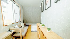 Ein gemütliches Schlafzimmer mit Schlafsofa, Bett, Holzbank und Schreibtisch mit Lampe.