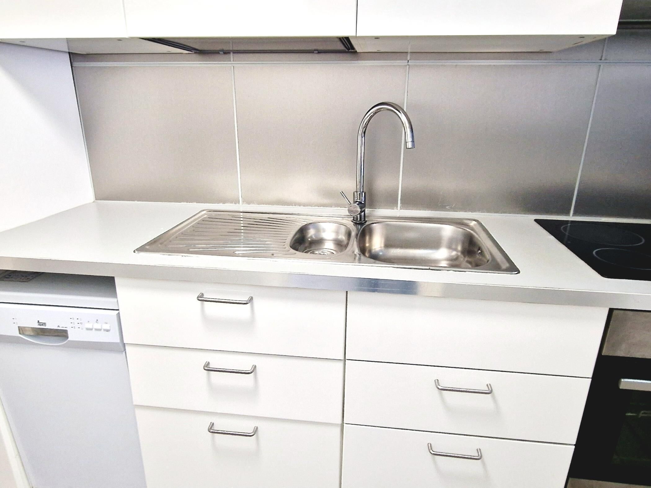 A modern kitchen with a stainless steel sink, two drawers, and a dishwasher.
