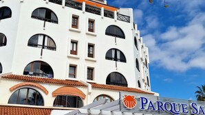 Een meerhoog hotel met een witte gevel, grote gebogen ramen en een bord met de tekst 'Parque SA'.