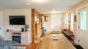 Una cocina amplia con una larga mesa de madera, taburetes de bar, un televisor y una chimenea.