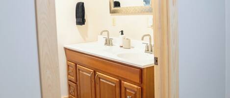 A bathroom with a wooden vanity, a large mirror, and a white sink.