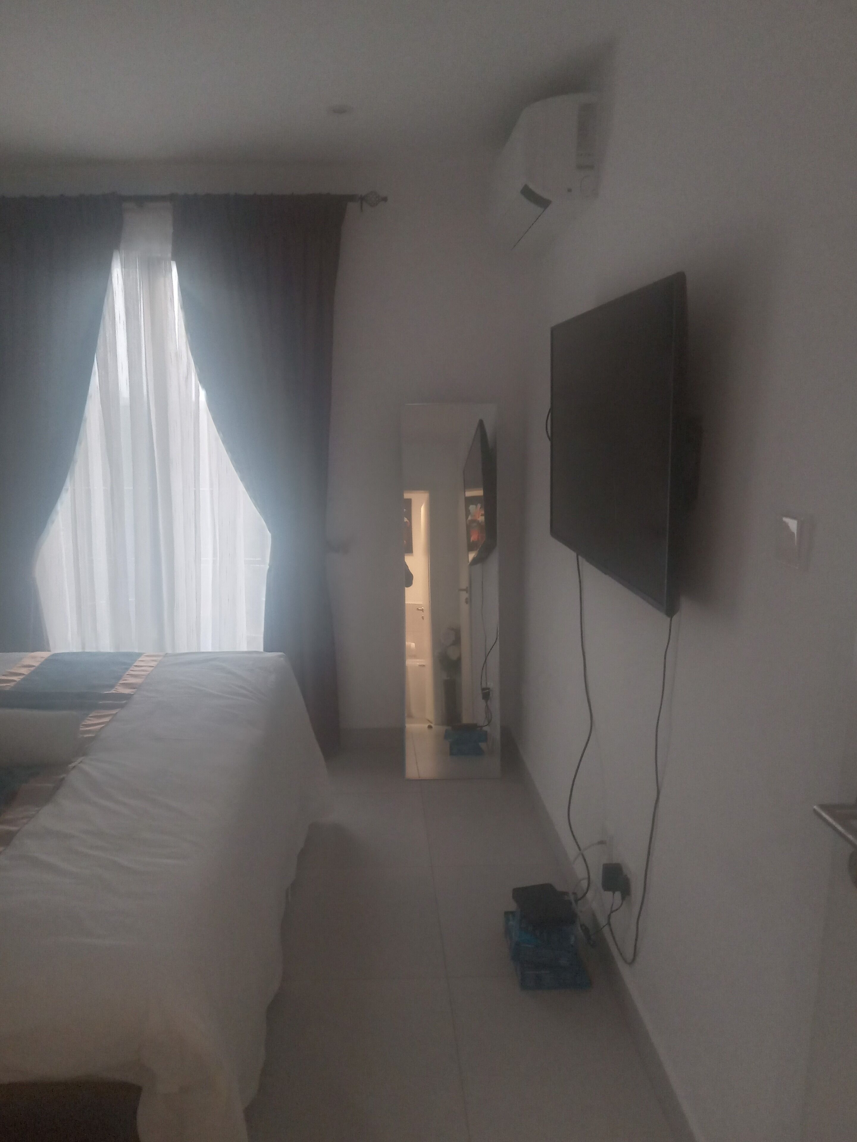 A hotel room with a bed, a TV mounted on the wall, and a door leading to a bathroom.