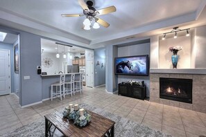 Una sala de estar moderna con chimenea, televisor y ventilador de techo.
