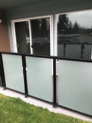 A balcony with a glass railing, a sliding glass door, and a view of a residential area. - Honeycomb hideout (Tukwila)