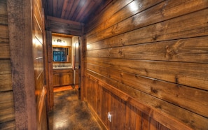 A wooden hallway with a sink and mirror, leading to a bathroom. - NEW HOME WITH POOL AND SLEEPS UP TO 28 (Leakey)