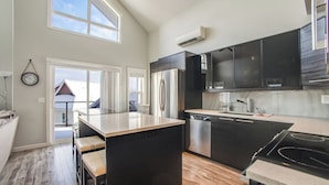 Een moderne keuken met zwarte kastjes, een centraal eiland en een vaatwasser.