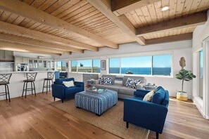A spacious living area with a kitchen, large windows, and a view of the ocean. - Beach House with Spectacular Ocean Views (Manhattan Beach)