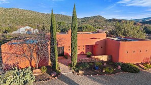 Un bâtiment moderne à la façade rouge, entouré d ’un jardin aménagé avec des cactus, offrant une vue dégagée sur les collines environnantes.