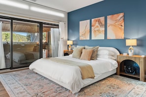 A bedroom with a large bed, a sliding glass door to a balcony, and two wall-mounted lamps. - Luxury Tigris House • Hot Tub • King Suites • Near Trails (Sedona)