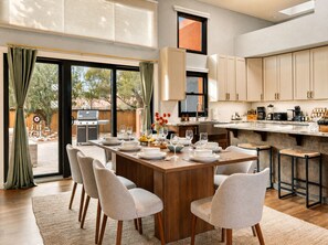 A modern kitchen with a dining area, large windows, and a view of the backyard. - Luxury Tigris House • Hot Tub • King Suites • Near Trails (Sedona)