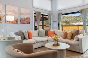 Ein modernes Wohnzimmer mit einem Ecksofa, einem runden Couchtisch und Kunstwerken an den Wänden.