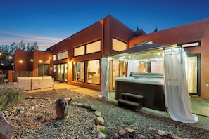 Ein modernes Haus mit Terrasse, ausgestattet mit Whirlpool, Sitzgelegenheit und einem gepflegten Garten.