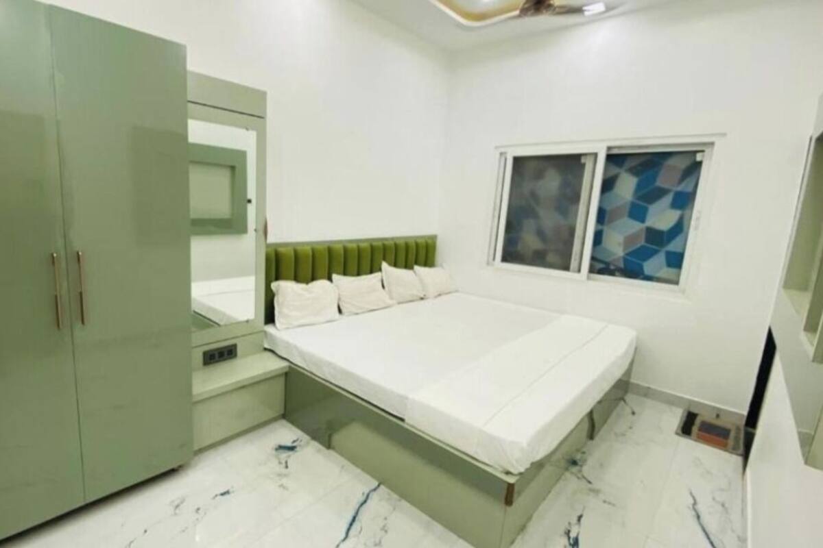 Un dormitorio con cama, armario, espejo y ventana con diseño geométrico.