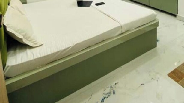 Une chambre à coucher moderne avec un lit, un ventilateur de plafond et une armoire verte.
