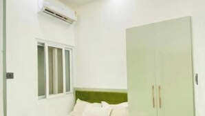 Une chambre à coucher comprenant un lit, une armoire, un appareil de climatisation et un ventilateur de plafond.