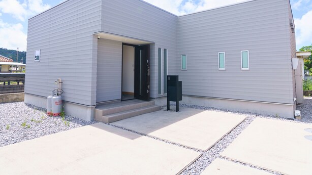 A modern building with a flat roof, a large open entrance, and a small outdoor seating area. - BURIKINA TERRACE (Nago)