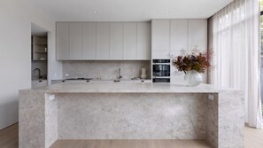A modern kitchen with a marble countertop, built-in cabinets, and a vase with dried flowers. - Atelier Windsor by Property Mums (Windsor)