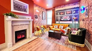 A living room with a fireplace, a sofa set, a coffee table, and a brick wall. - "Friends" House/Mins to Stadiums/Free Parking/Hot Tub/Pets Welcomed (Pittsburgh)
