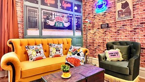 A cozy living room with a brick wall, a yellow sofa, a green armchair, and a coffee table. - "Friends" House/Mins to Stadiums/Free Parking/Hot Tub/Pets Welcomed (Pittsburgh)