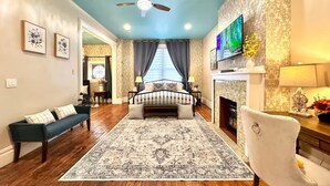 A spacious living room with a large bed, a fireplace, a TV, and a ceiling fan. - "Friends" House/Mins to Stadiums/Free Parking/Hot Tub/Pets Welcomed (Pittsburgh)