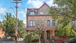 A two-story stone building with a red roof, a front porch, and a stop sign in the foreground. - "Friends" House/Mins to Stadiums/Free Parking/Hot Tub/Pets Welcomed (Pittsburgh)