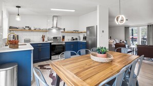 Una cucina moderna con mobili azzurri, un tavolo da pranzo in legno e un frigorifero in acciaio inossidabile.