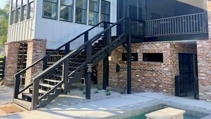 Una casa moderna de dos pisos con piscina, una escalera y un ventanal grande.
