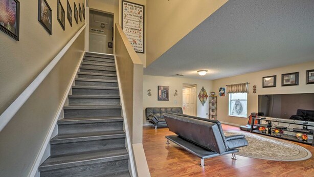 A staircase leading to a living area with a sofa, a fireplace, and framed pictures on the walls. - 5BR Home near Disney w/ Arcade & Private Pool (Davenport)