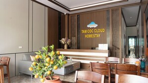 A modern hotel lobby with a reception desk, seating area, and decorative elements. - Tamcoc Cloud Homestay (Nam Hoa Lu)