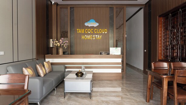 A modern reception area with a reception desk, a sofa, a coffee table, and a dining area with chairs. - Tamcoc Cloud Homestay (Nam Hoa Lu)
