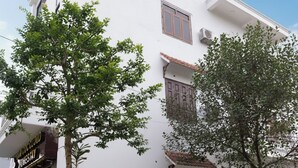 A white building with a balcony, potted plants, and outdoor seating. - Tamcoc Cloud Homestay (Nam Hoa Lu)