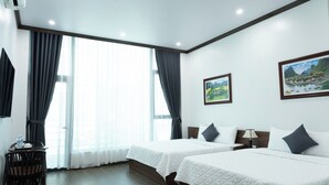 A hotel room with two beds, a desk, and a chair. There are curtains, a painting on the wall, and a window with a view. - Tamcoc Cloud Homestay (Nam Hoa Lu)