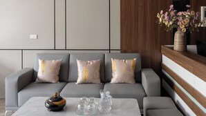 A modern living room with a grey sofa, a coffee table, and a wooden accent wall. - Tamcoc Cloud Homestay (Nam Hoa Lu)