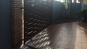 Una entrada con puerta de rejas, pared de ladrillo y suelo de baldosas.