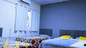 Habitación de hotel con dos camas, una ventana con cortinas, un equipo de aire acondicionado y vistas al exterior.