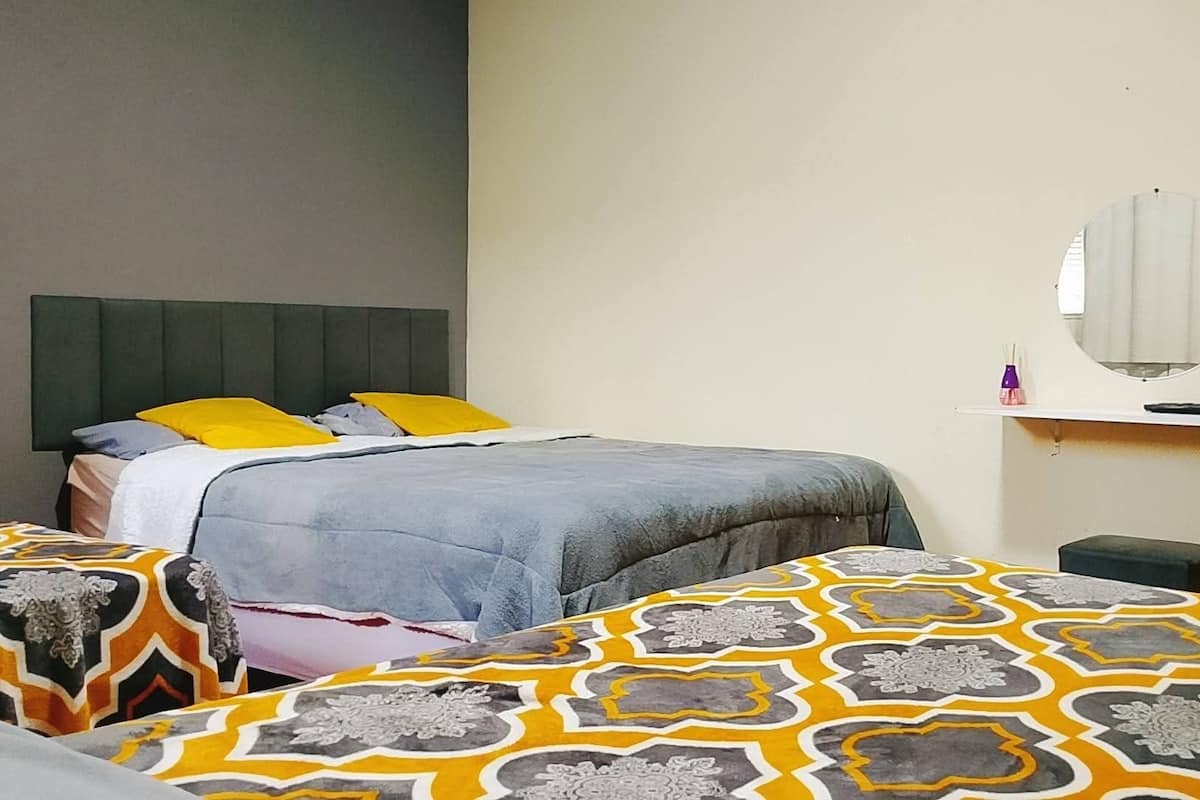 Habitación de hotel con cama, dos mesitas de noche, un espejo y un calentador de pared.