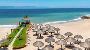 A beach resort with thatched umbrellas, lounge chairs, and a small pavilion. - Beachside Studio Near Downtown Puerto Vallarta (Puerto Vallarta)