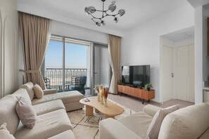 Ein modernes Wohnzimmer mit einer Sofagarnitur, einem Couchtisch, einem Fernseher und einem Balkon mit Blick.