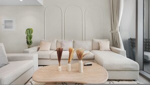 A modern living room with a sectional sofa, a coffee table, and decorative vases. - 1BR Retreat Near Burj Khalifa (Dubai)