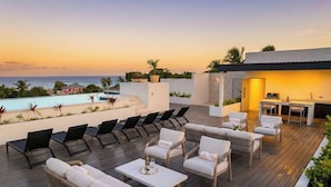 Eine Dachterrasse mit Sitzgelegenheiten im Freien, einem Pool und einer Bar.